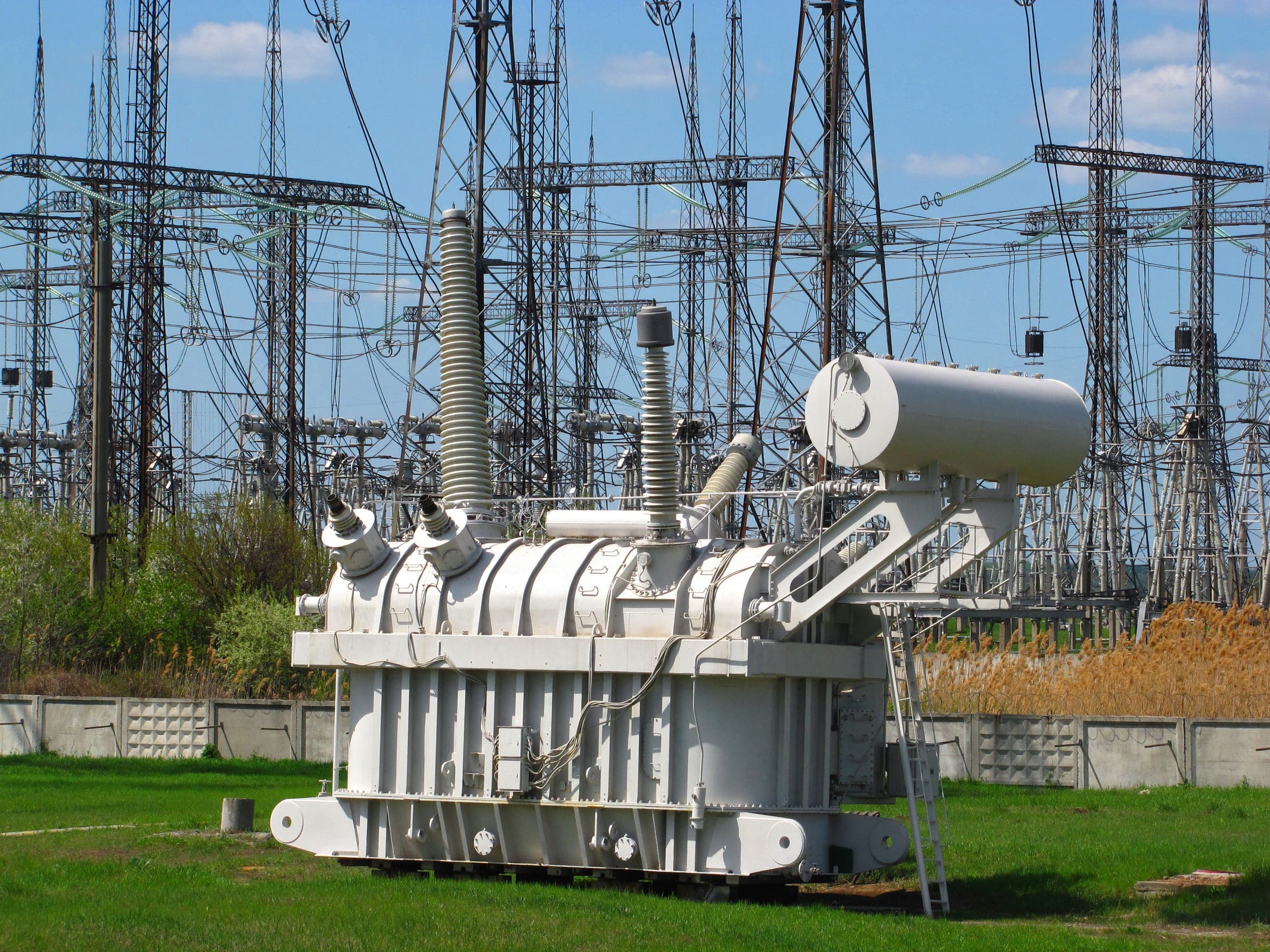 Large oil-immersed power transformer with conservator and high-voltage bushings in a substation